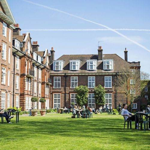 Regent's University London building exterior with students sitting at tables in the garden